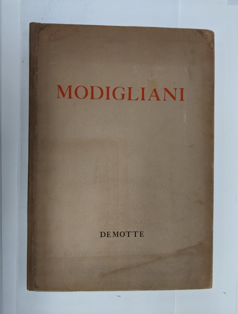 The front cover of the book is shown after treatment has been completed. The dust cover is a dark brown paper and the title 'Modigliani' is printed in red text across the front.
